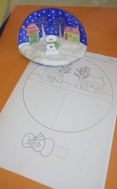 a paper plate sitting on top of a table next to a snowman cut out