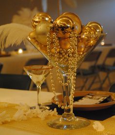 a table topped with a martini glass filled with gold decorations