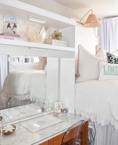 a white bed sitting next to a desk with a mirror on the top of it