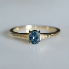 a gold ring with a blue topazte in the center on a white surface