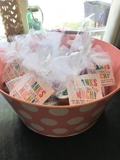 a pink polka dot bowl filled with lots of little tags and plastic bags on top of it