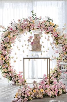 the wedding cake is surrounded by pink and yellow flowers on top of a white table