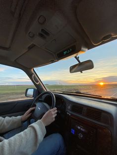 a woman driving a car on the highway at sunset