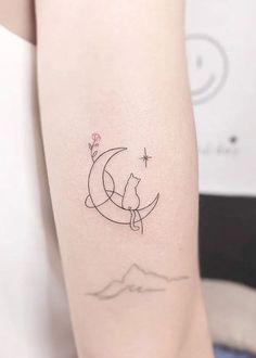 a woman's arm with a small cat sitting on the moon and stars above it