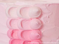 a close up of a pink cake with icing on it's side and the top layer is white