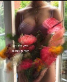 a woman holding flowers in her hands with the words i am my own secret garden