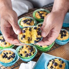 a person holding up a muffin in front of some other muffins