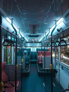 the inside of a bus with red seats and blue flooring is lit up at night