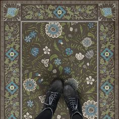 a person standing in front of a rug with flowers on it