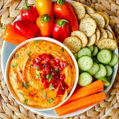 an assortment of vegetables and dips on a plate with crackers in the background