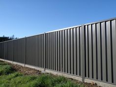 a large metal fence next to a grassy field