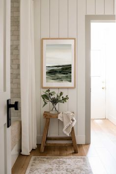 a painting hanging on the wall next to a wooden bench with a plant in it