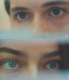 two blue eyes are seen through a glass window with the reflection of another person's face