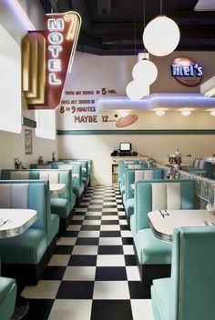 the interior of a diner with checkered flooring and neon signs hanging from the ceiling