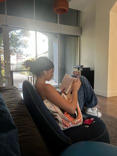 a woman sitting on a couch reading a book