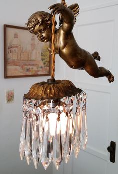 a chandelier hanging from the ceiling with an angel figurine on it