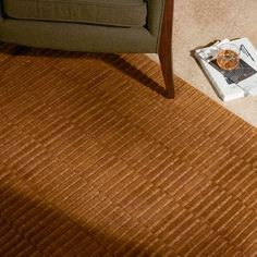 a brown rug on the floor next to a chair and coffee table with a magazine