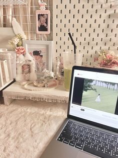 an open laptop computer sitting on top of a white table next to pictures and photos