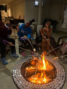 people sitting around a fire pit with sticks sticking out of it