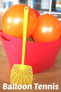 an orange and yellow ball in a red bucket with a rake on it that says balloon tennis