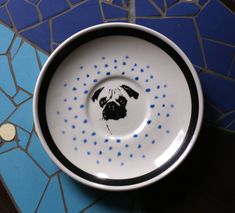 a bowl with a dog drawn on it sitting on a blue and white tile floor