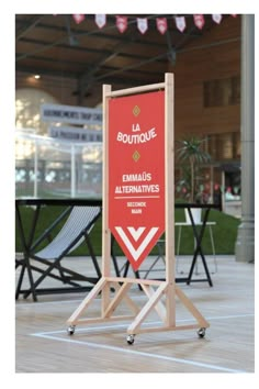 a red sign sitting on top of a wooden floor in front of chairs and tables