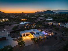 an aerial view of a home in the desert at dusk with mountains in the background