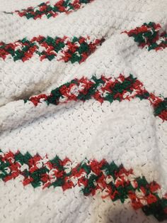 a white crocheted blanket with red and green trim