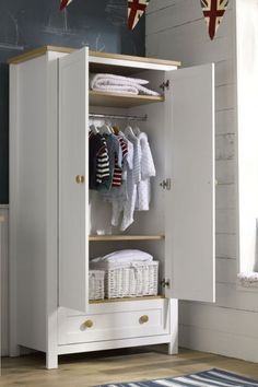 a white wardrobe with clothes hanging on it's doors and drawers in a room