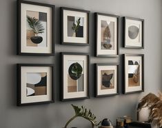 a bunch of pictures hanging on the wall above a table with some plants in it