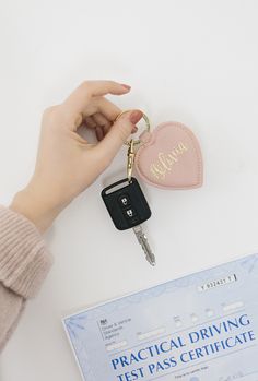 a person is holding a car keychain and it has a heart shaped case