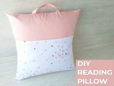 a pink and white pillow sitting on top of a wooden floor next to a wall