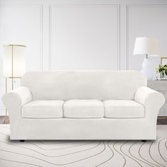 a white couch sitting on top of a rug in a living room next to a lamp