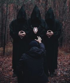 a group of people in black hoodeds with their hands on each other's faces