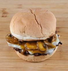 a cheeseburger with mushrooms and onions on a wooden surface, ready to be eaten