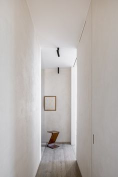 an empty hallway with white walls and wood flooring is seen in this image from the inside