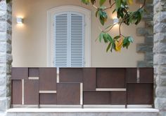 a window with shutters is shown behind a wall made out of wood and stone