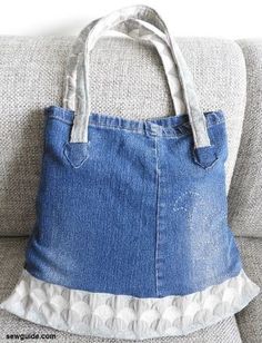 a blue jean purse sitting on top of a couch next to a gray sofa cushion