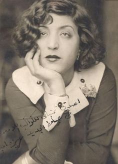 an old black and white photo of a woman with her hand on her chin looking at the camera