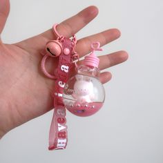 a hand holding a small pink key chain