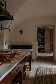 an archway leads to a wine cellar in the kitchen and into the dining room, there is a rug on the floor