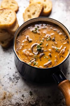 a black pot filled with soup next to slices of bread