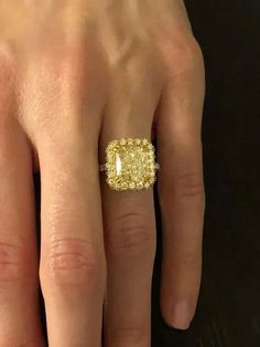 a woman's hand with a yellow diamond ring on it