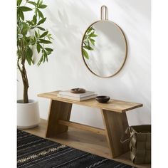 a wooden table with a mirror on it next to a potted plant and rug