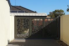 a gate with an intricate design on the top and bottom, in front of a house