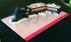 a birthday cake that looks like a train is on the table with writing on it