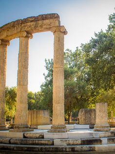 an old roman temple with columns and trees in the background