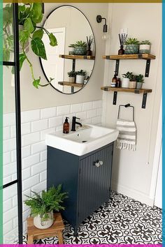 a white sink sitting under a mirror next to a wooden shelf filled with potted plants