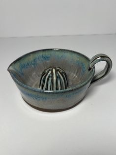 a blue and white ceramic bowl with a handle on the bottom that is shaped like a boat