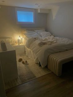 an unmade bed sitting in a bedroom next to a night stand with two lights on it